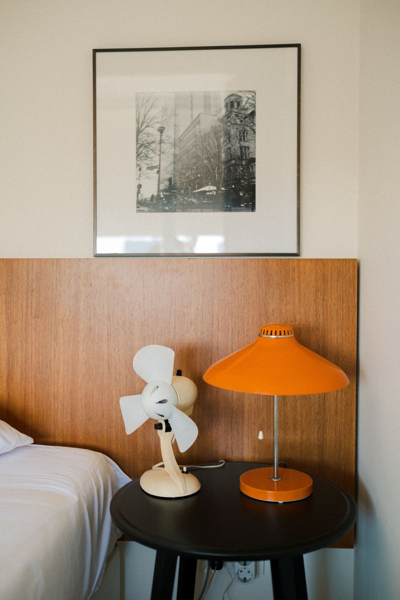 Warm wood bedside with an orange table lamp — room inspiration, not a WARMELO product