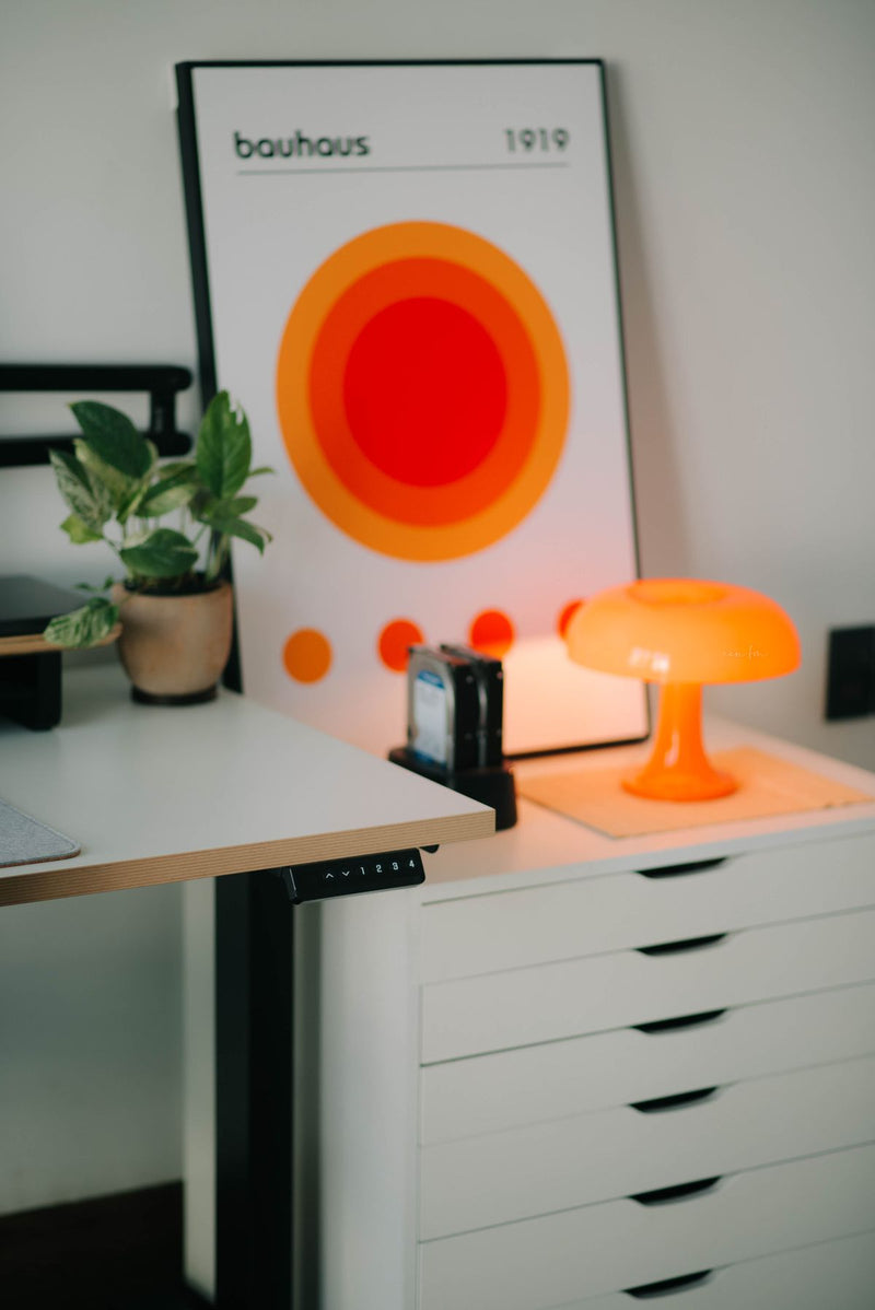 Orange lamp beside a home workspace and plant — room inspiration, not a WARMELO product